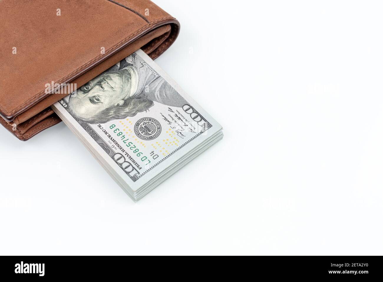Portafoglio in pelle marrone con dollari isolati su sfondo bianco. Disposizione piatta. Primo piano della foto. Contanti di centinaia di dollari fatture Foto Stock