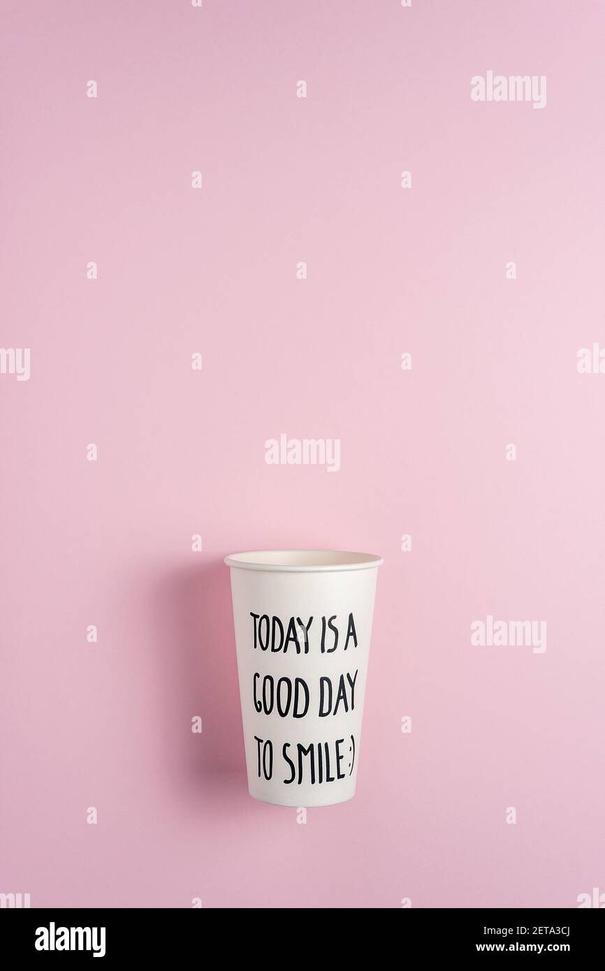 Tazza di carta bianca su sfondo rosa. Concetto creativo di bevanda minimale. Foto Stock