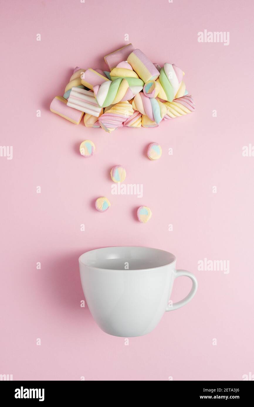 Marshmallow a forma di nuvola piovosa con coppa bianca su sfondo rosa. Concetto creativo minimo di cibo dolce per le vacanze. Foto Stock