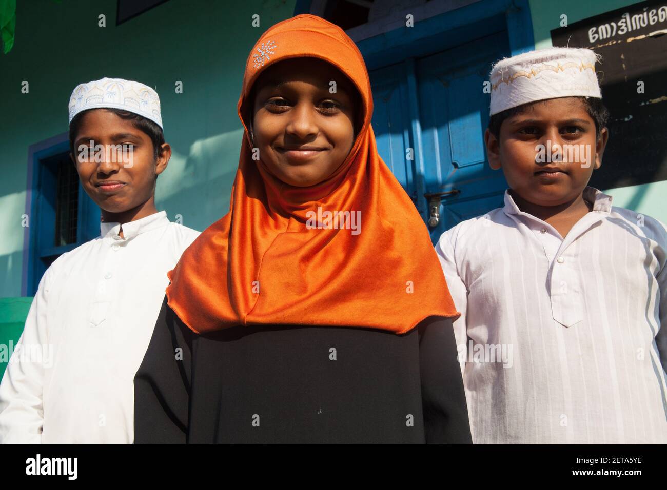 Ritratto di una ragazza musulmana che indossa un hijab con i suoi due fratelli che indossano cappelli Taqiyah ad Alleppey, Kerala, India Foto Stock