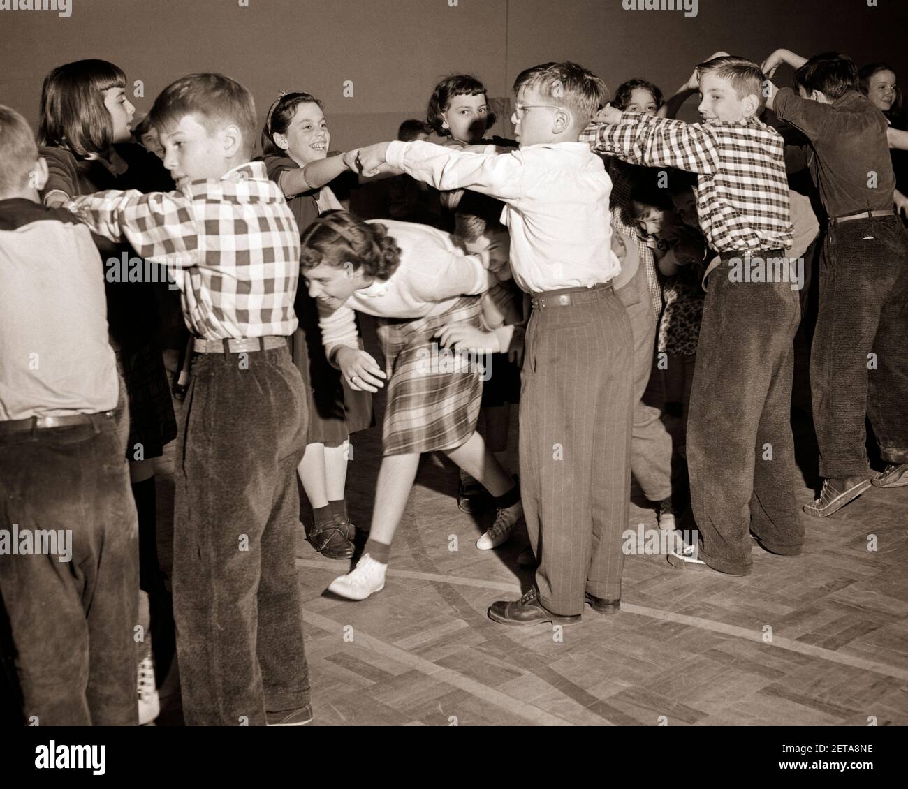 1950 RAGAZZI E RAGAZZE PIAZZA DANZANTE VIRGINIA BOBINA CAMMINARE SOTTO ARCO DI MANI COLLEGATE - D115 HAR001 HARS FISICO A LUNGHEZZA INTERA FITNESS MASCHI INTRATTENIMENTO B&W SCUOLE GRADO FELICITÀ ARCO TEMPO LIBERO E. ECCITAMENTO BASSO ANGOLO RICREAZIONE PRIMARIA POPOLARE AMICHEVOLE ELEGANTE COOPERAZIONE LEGATA SCUOLA ELEMENTARE GIOVANI TOGETHERNESS BIANCO E NERO ETNIA CAUCASICA HAR001 VECCHIO STILE Foto Stock