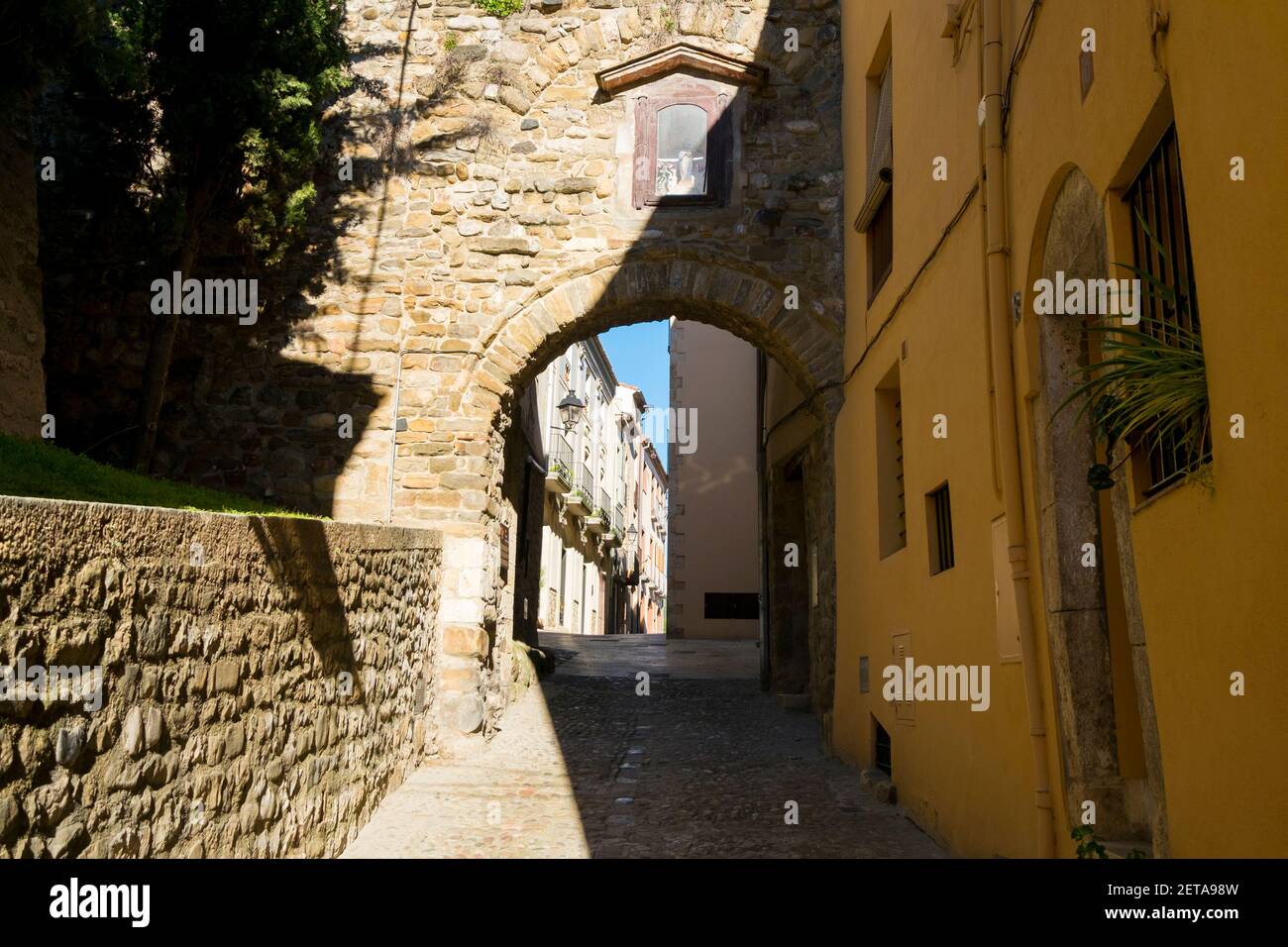 Una tipica antica strada medievale ad arco in pietra nella città di Besalú, Spagna. Pittoresca, città vecchia, restaurata, stradina. Foto Stock