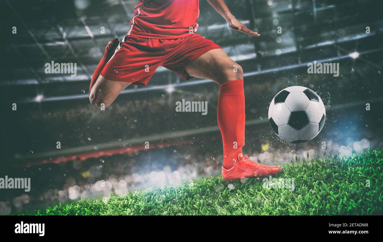 Primo piano di una scena di calcio durante la partita notturna con giocatore in una divisa rossa calcia la palla con il potere Foto Stock