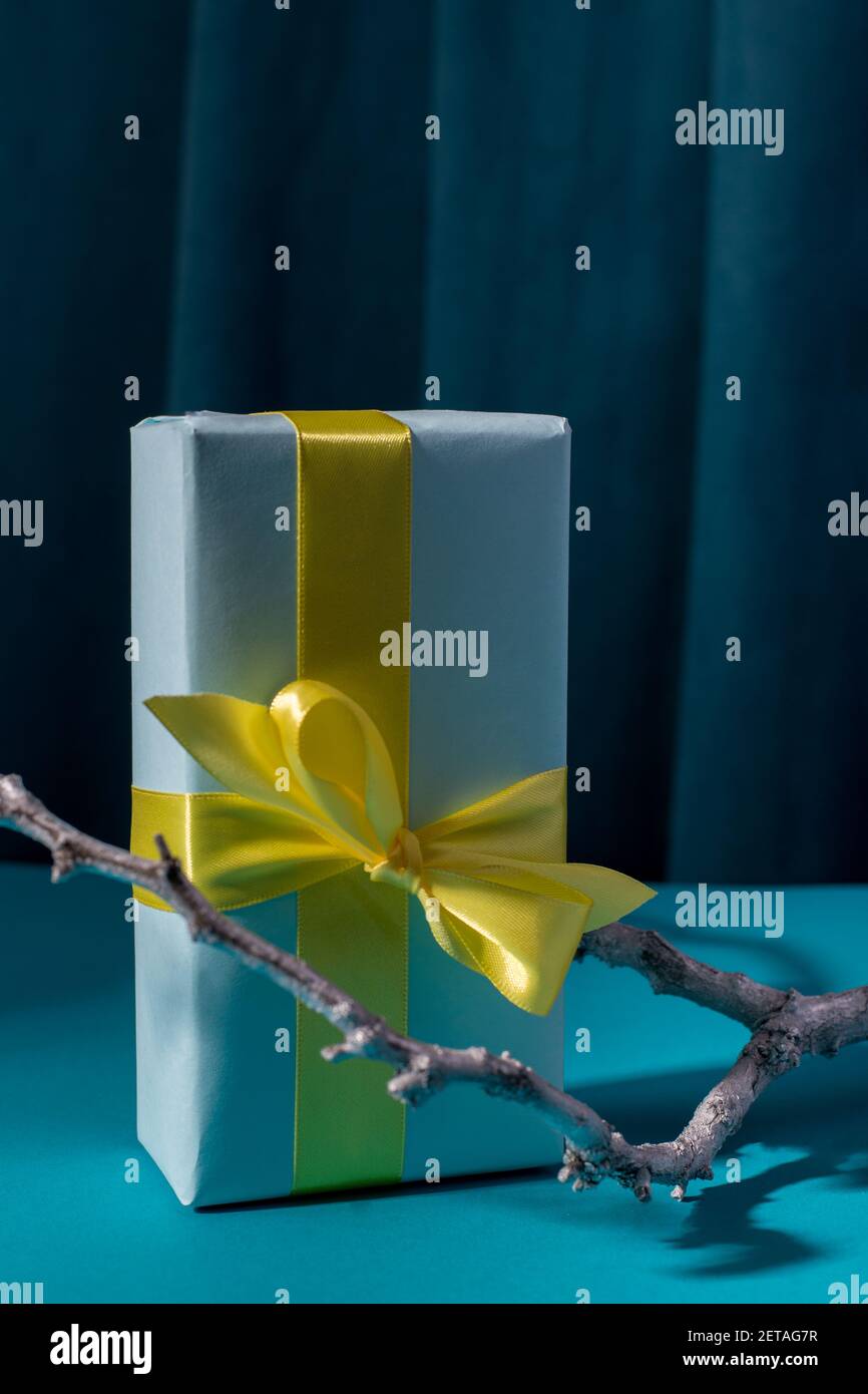 Confezione regalo con arco giallo su sfondo blu intenso e tenda. Foto Stock