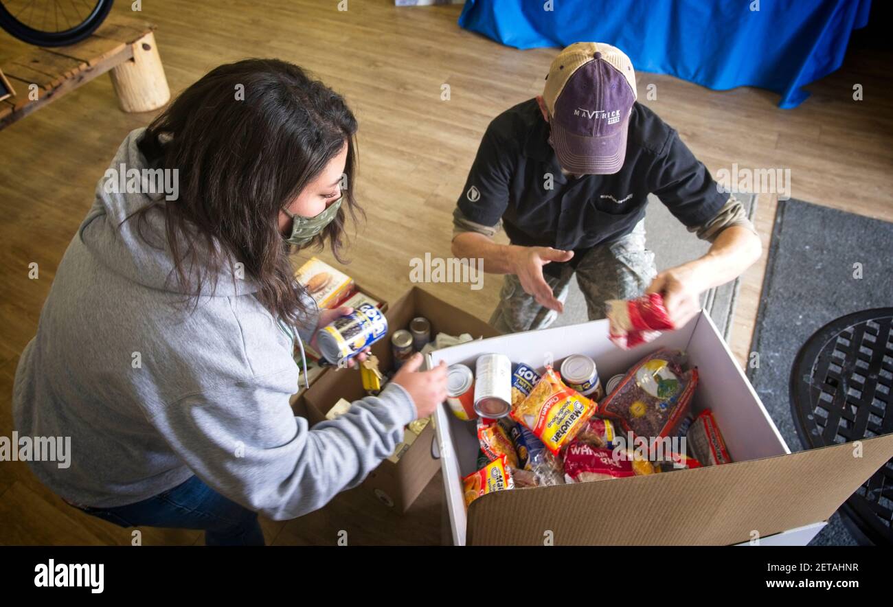 STATI UNITI - FEB. 26, 2021: Gabriela Lamas Project Coordinator per il progetto Ampersand Pantry e Gary Moon di Maverick Bikes & Cafe caricare il cibo Foto Stock