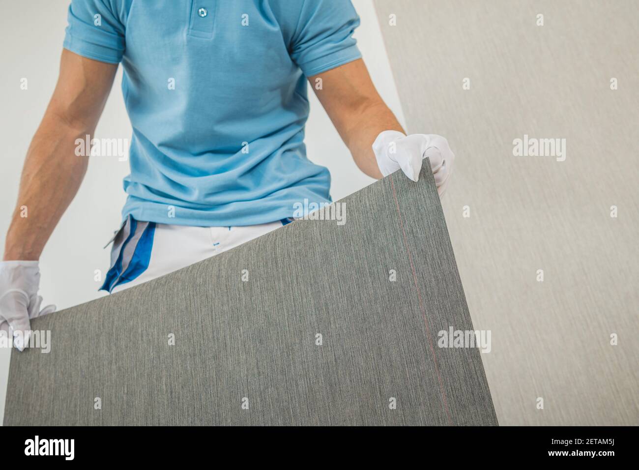 Uomini caucasici nei suoi 40 preparare nuovo wallpaper in vinile per Wallcover all'interno pulito stanza bianca interno dell'appartamento. Foto Stock