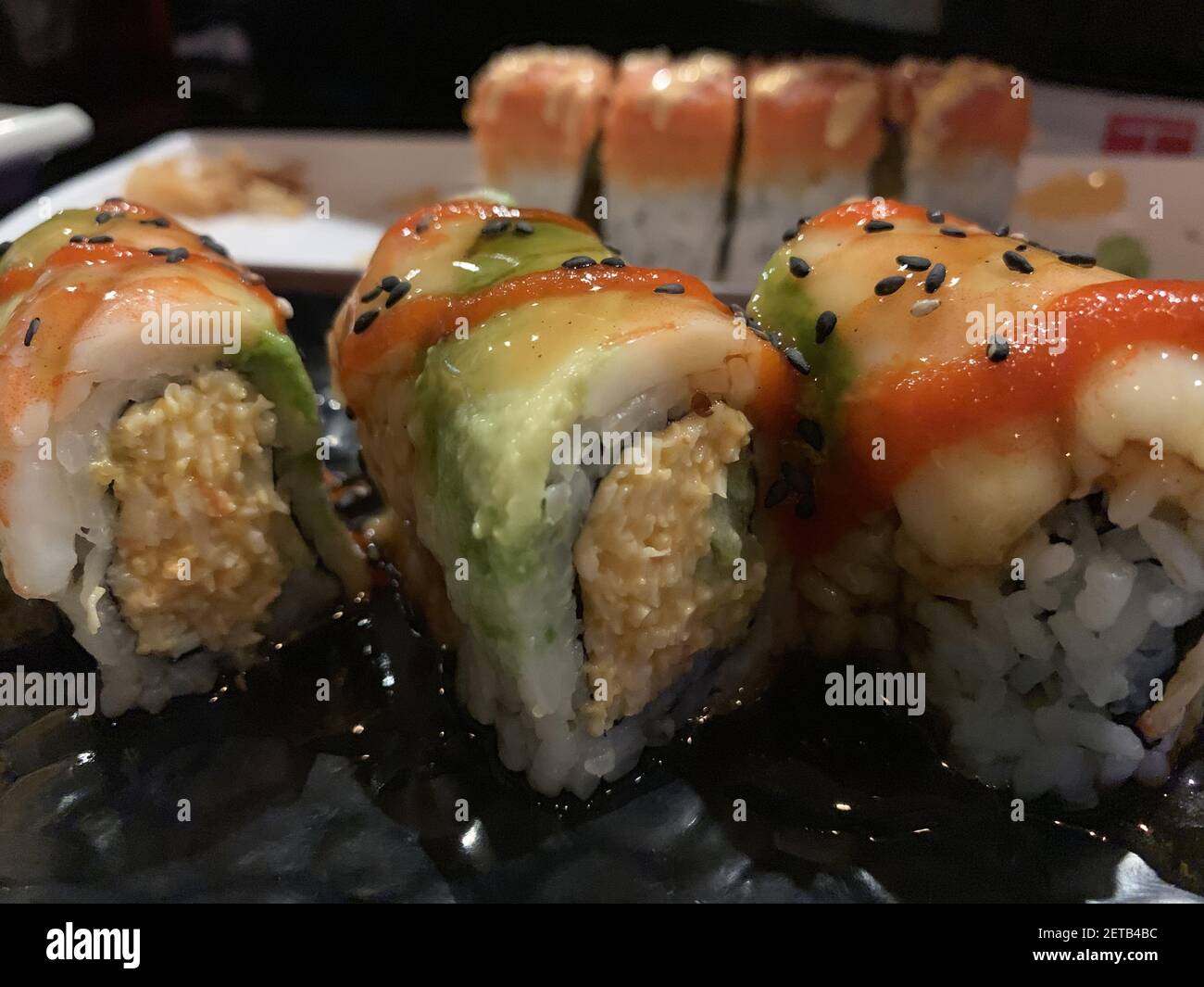 Un primo piano di diversi tipi di sushi con tonno, avocado, granchio, semi di sesamo Foto Stock