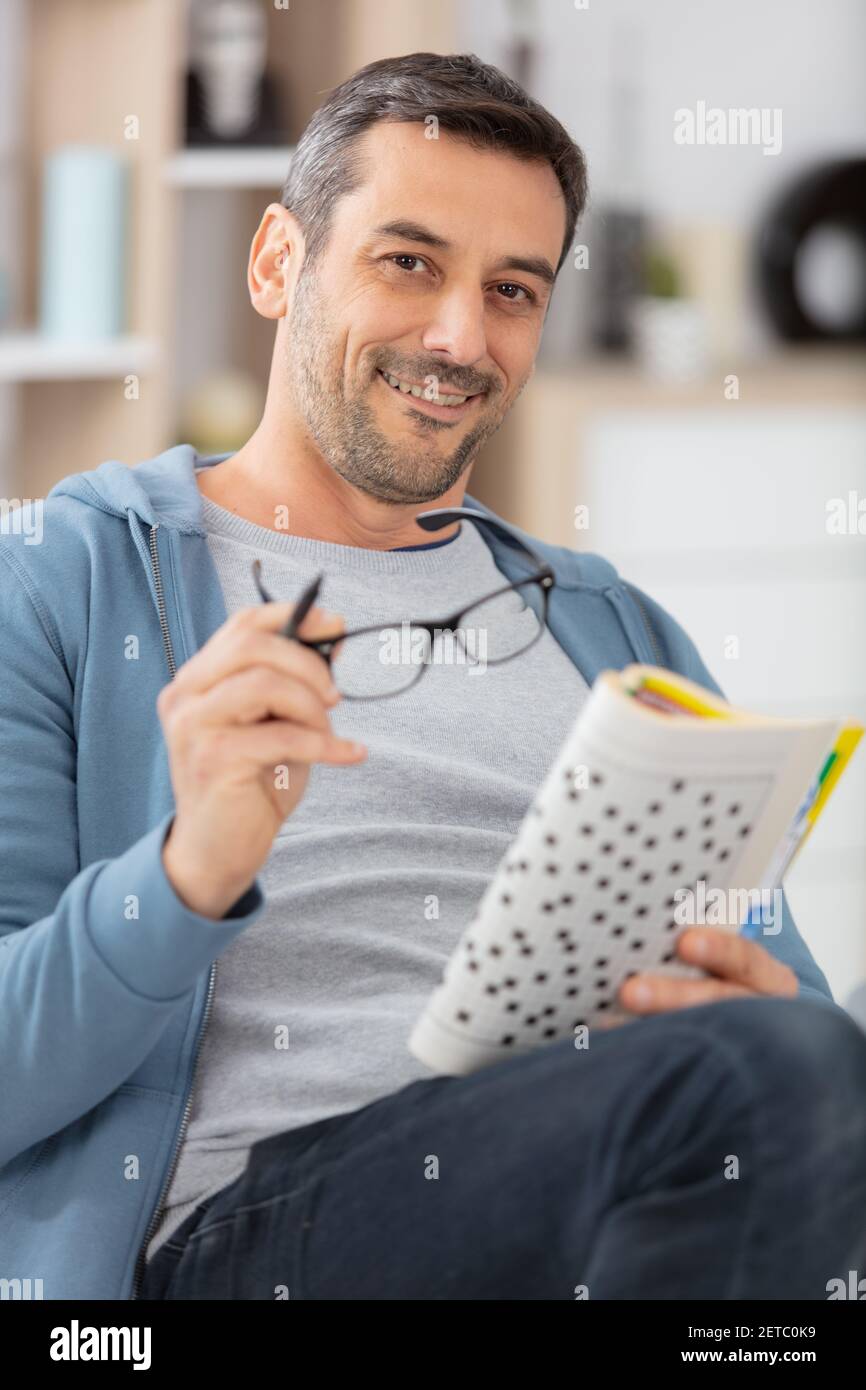 uomo maturo seduto sul divano facendo crosswords Foto Stock