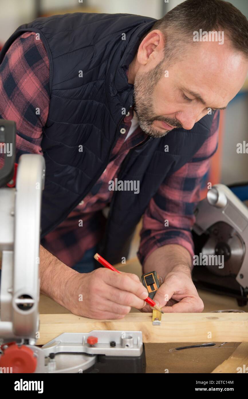 lavoratore dell'appaltatore che utilizza la sega circolare con azionamento a vite senza fine manuale Foto Stock