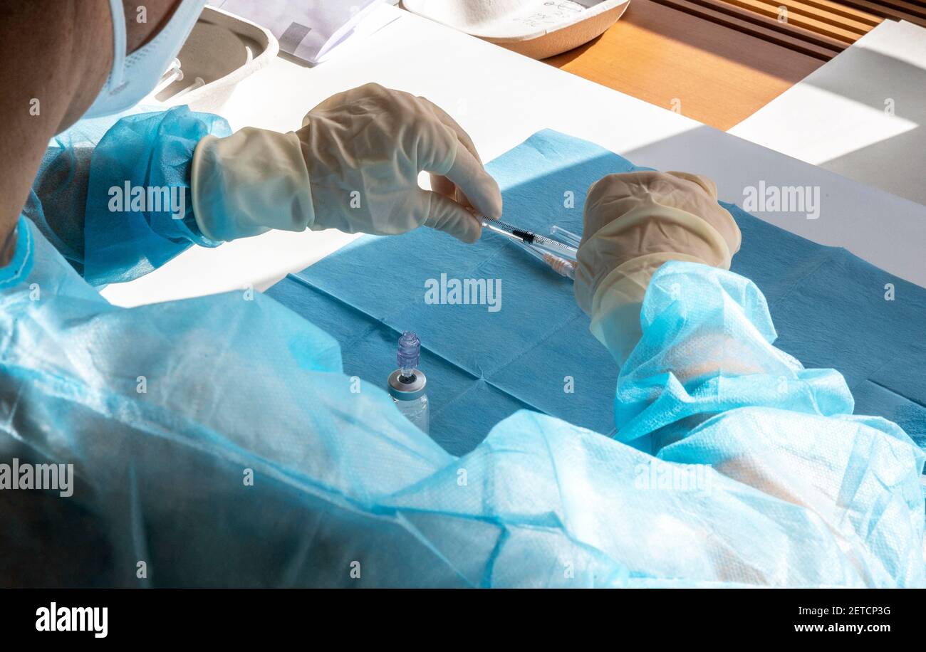 Un medico prepara un'iniezione di vaccino durante una massiccia giornata di vaccinazione in un centro sanitario. Siringhe in preparazione e pronte all'uso. Foto Stock