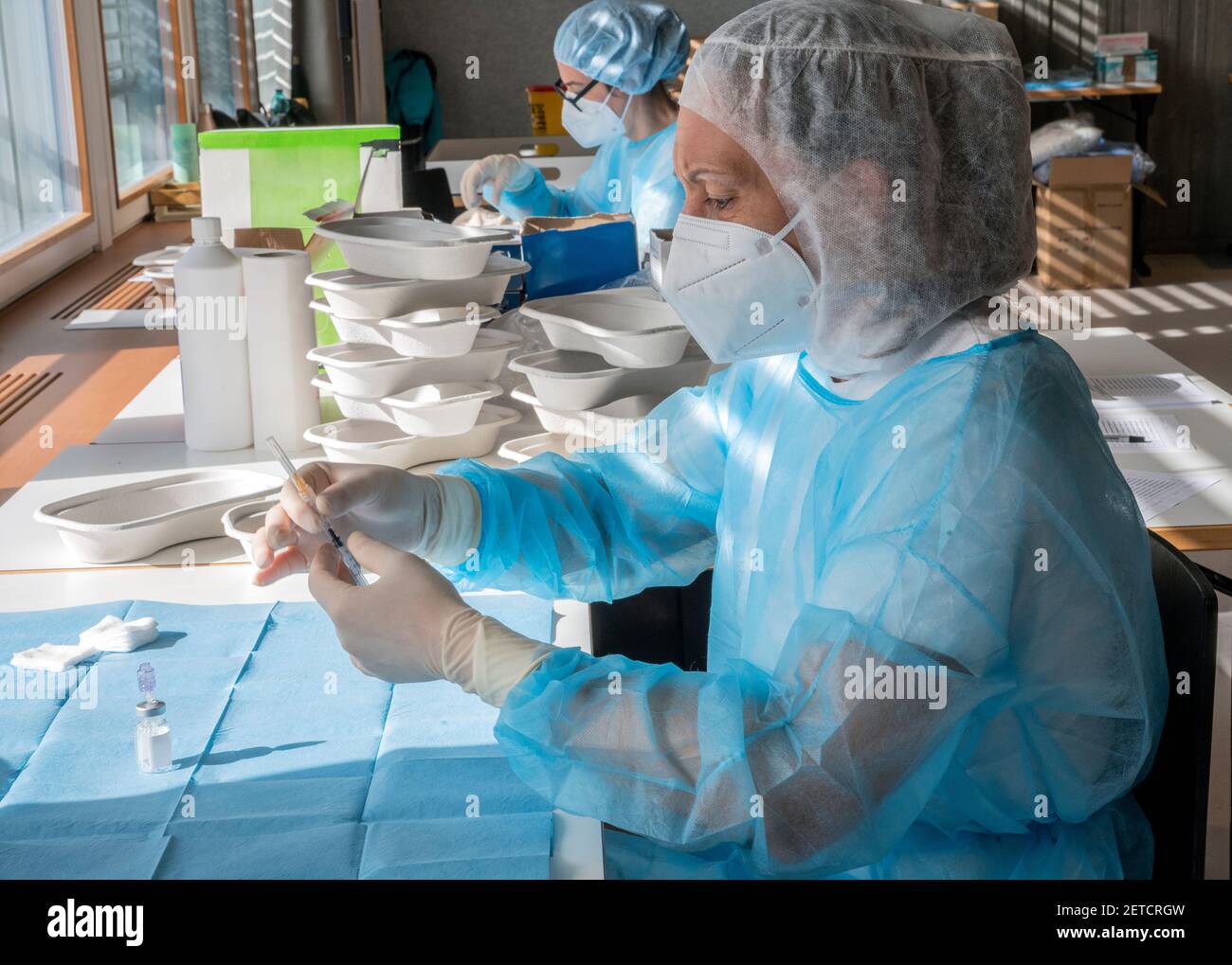 Un medico prepara un'iniezione di vaccino durante una massiccia giornata di vaccinazione in un centro sanitario. Siringhe in preparazione e pronte all'uso. Foto Stock