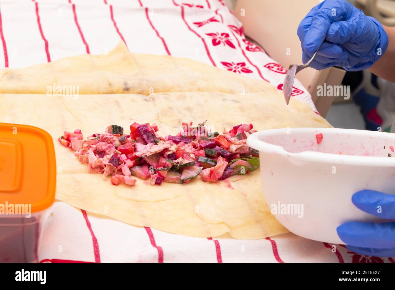 cucina shawarma in una scuola di lezione di lavoro. verdure in pita pane. parti di mani da vicino. fuoco selettivo Foto Stock