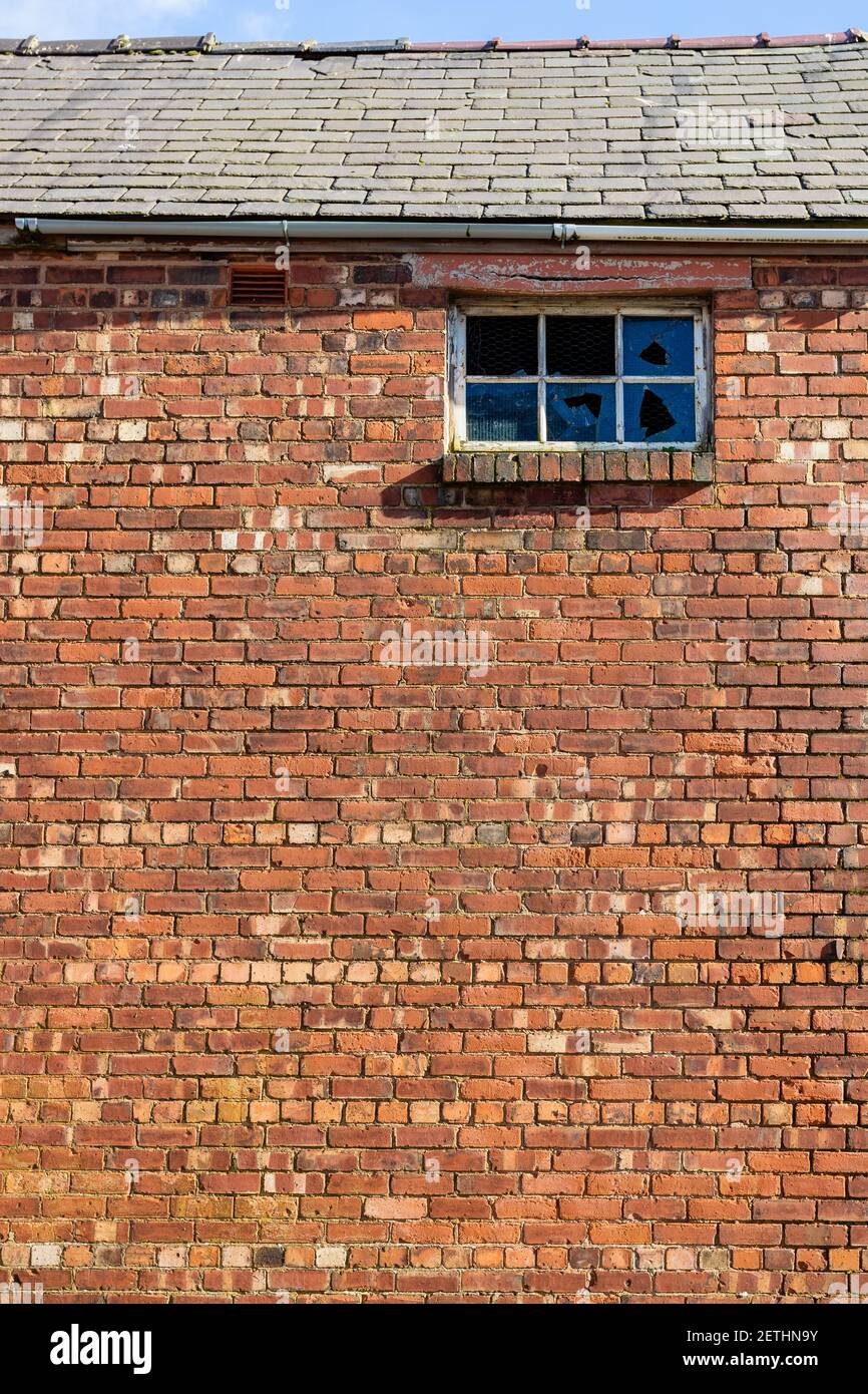 Muro di mattoni rossi con finestra rotta. Ripresa in modo grafico e artistico. Foto Stock