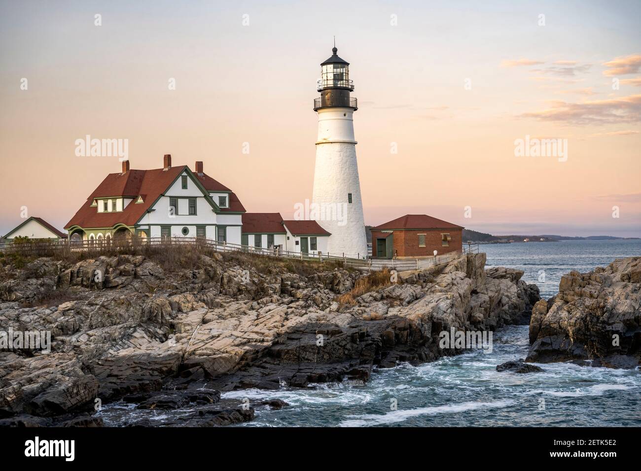 Faro illuminato dal sole che tramonta su un promontorio roccioso Sullo sfondo di un cielo nuvoloso sull'Atlantico Costa a Portland, Maine New Engla Foto Stock