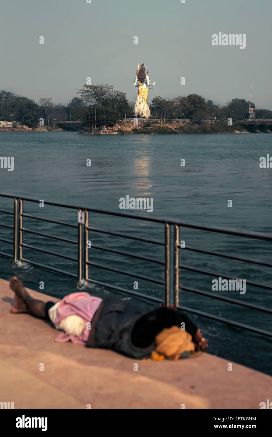 Statua del Signore Shiva Mahadeva vicino al fiume Ganga in Haridwar con una sola persona con faccia nascosta che dorme sul Piedi di Dio Foto Stock