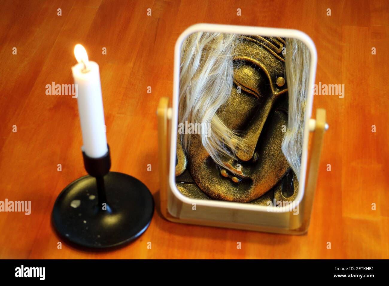 Illusione astratta dello specchio - Buddha con i capelli biondi e a. candela Foto Stock