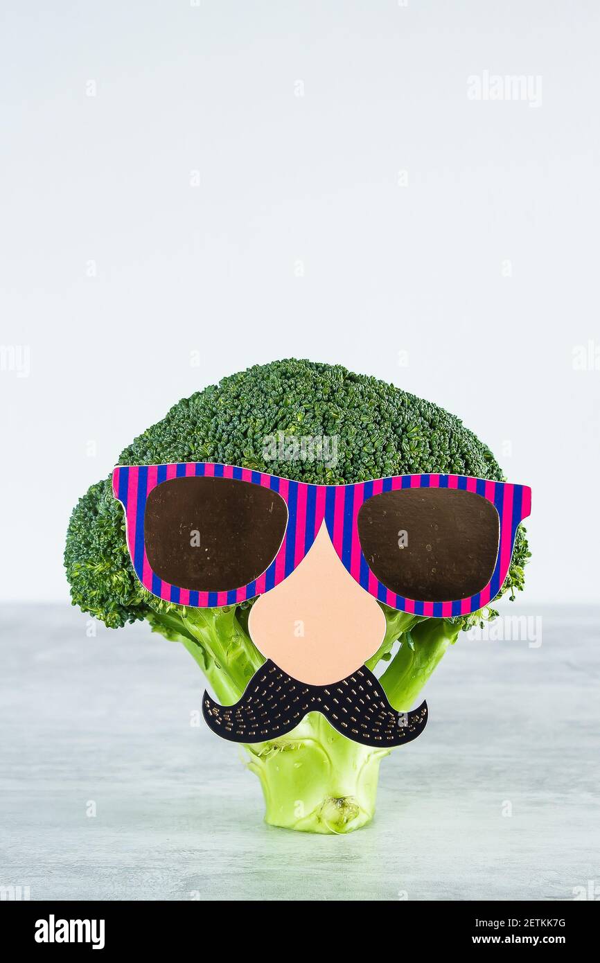 Divertenti verdure carine broccoli. Broccoli con baffi di carta e bicchieri. Concetto di cibo sano. Foto Stock
