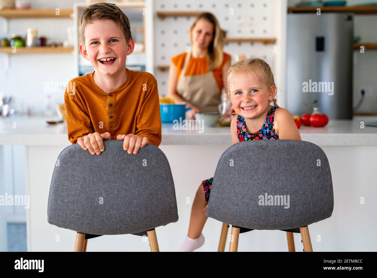 Famiglia felice a casa. Madre e bambini in cucina. Carino piccolo aiutante. Foto Stock