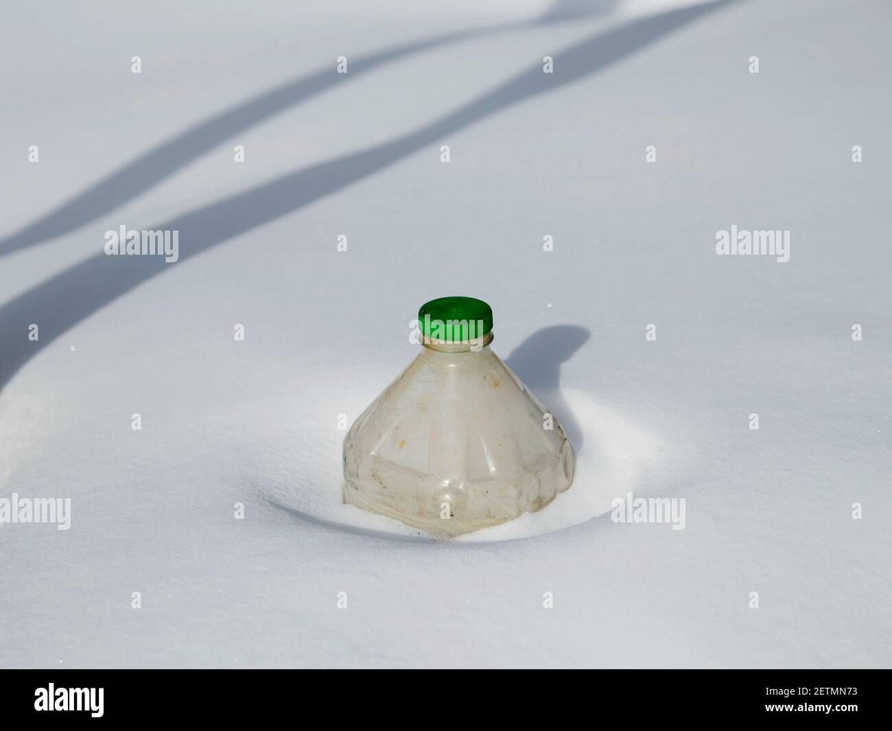 Vecchia bottiglia di plastica coperta di neve che non è stata smaltita. Foto Stock