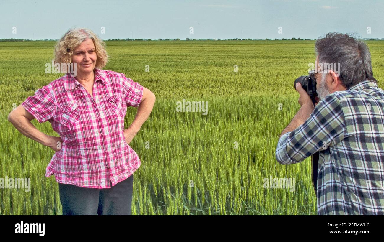 Il fotografo fotografa il suo modello in grano giovane. Foto Stock