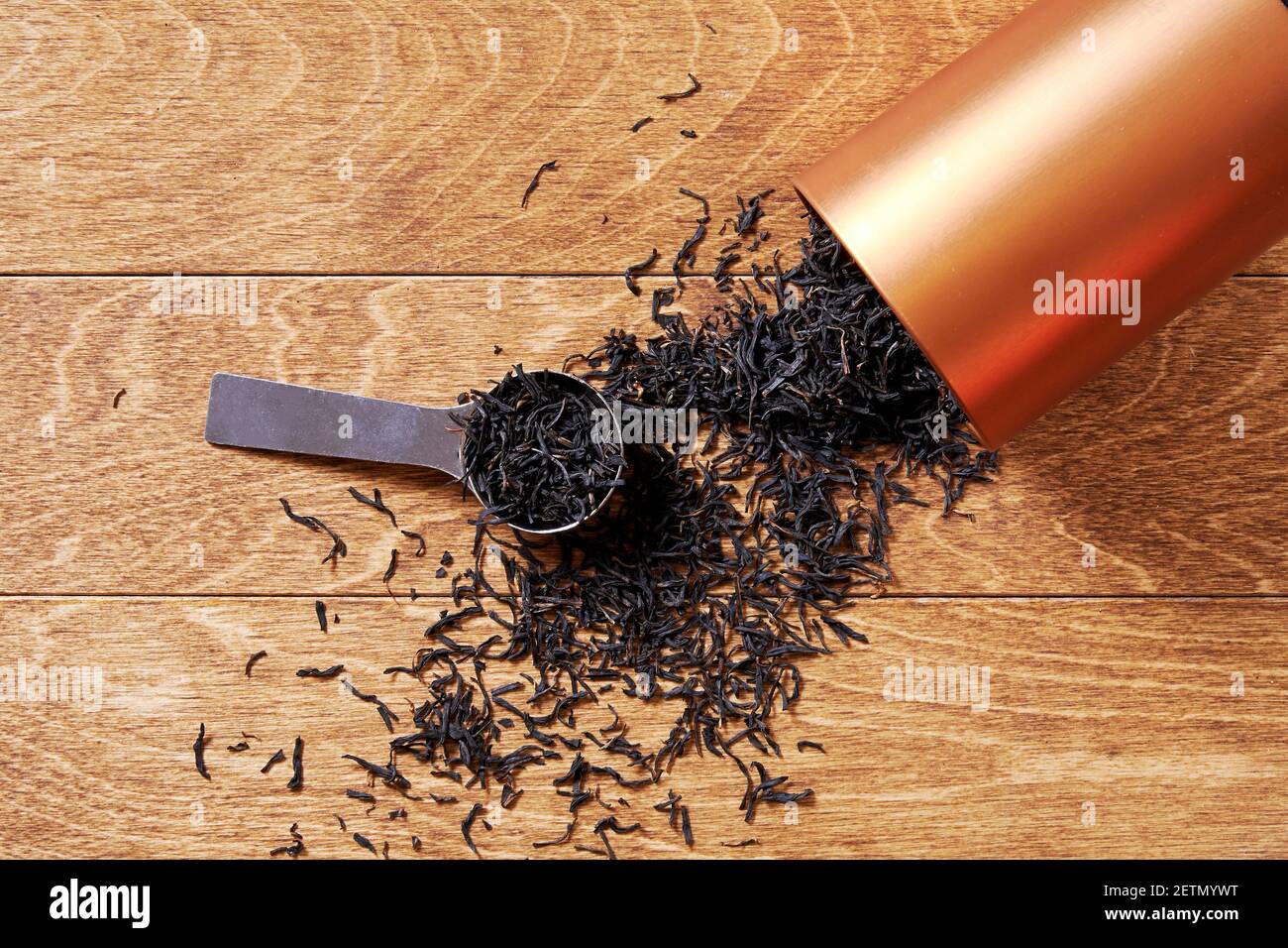 Tè nero, distribuito sul tavolo di legno con vasetto arancione e cucchiaio. Gli sfondi della cerimonia del tè Foto Stock