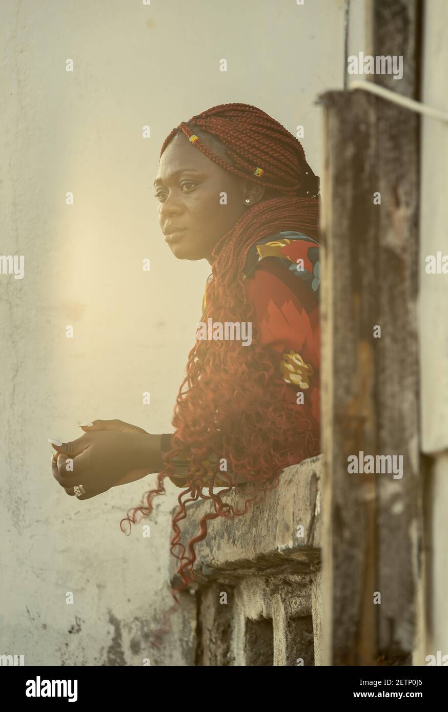 Donna africana che si affaccia sul mare da un balcone Al tramonto ad Accra Ghana Africa Occidentale Foto Stock