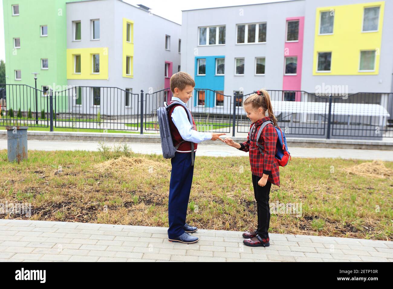 Bambini con borse portadocumenti sopra le spalle sullo sfondo della scuola. Foto Stock