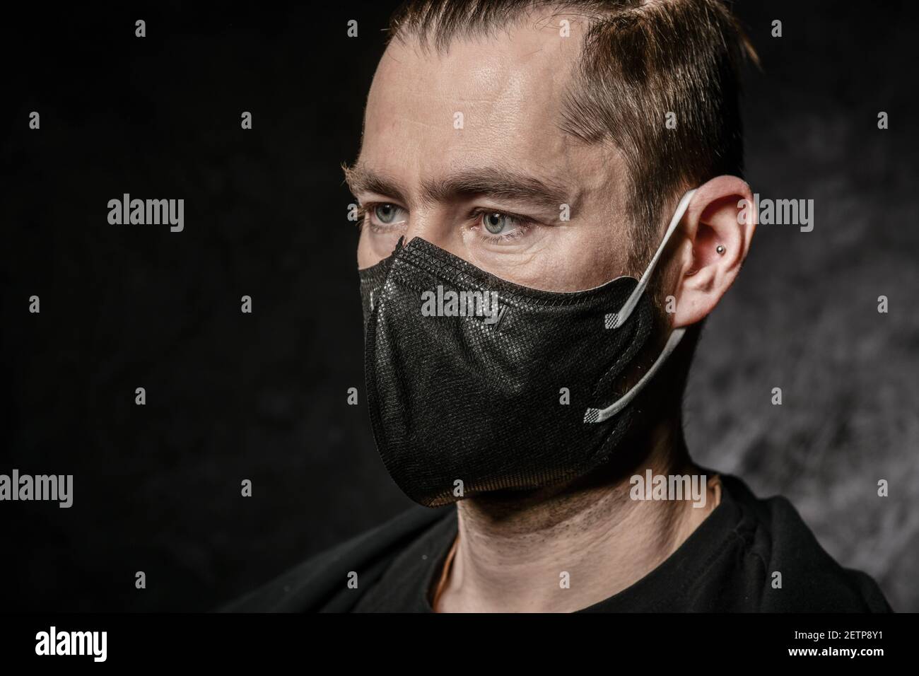 Un uomo con maschera nera sul viso uno sfondo scuro nello studio Foto Stock