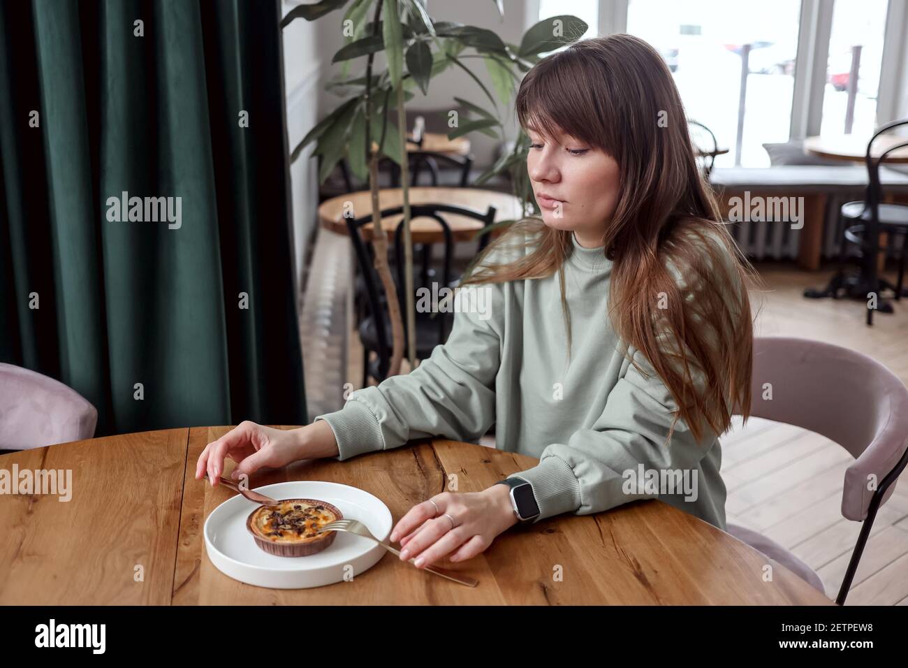 Bella donna seduta in caffè mangiare torta. Colazione nel caffè. Una ragazza è seduta ad un tavolo in un caffè. Foto Stock