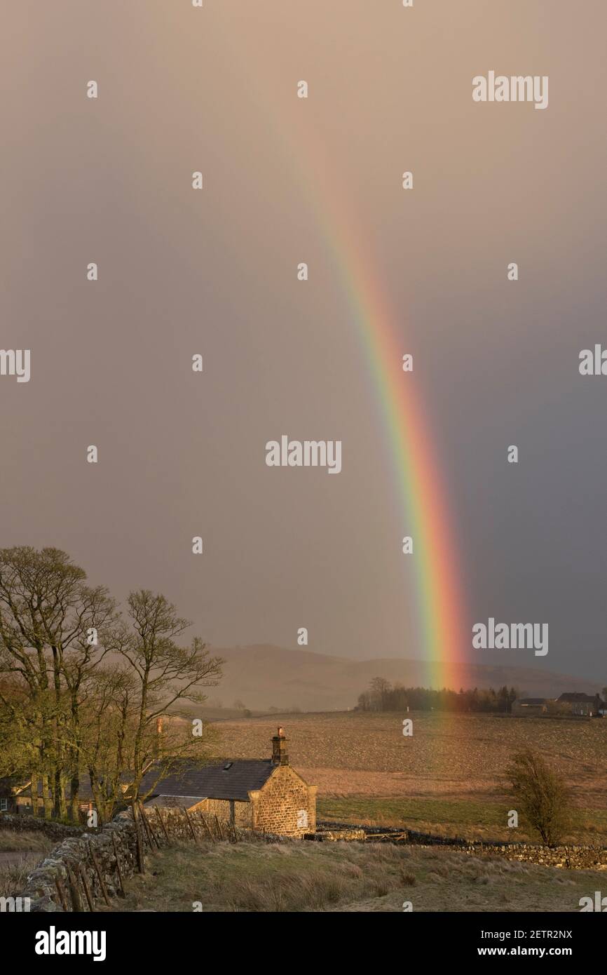 Un arcobaleno si illumina brillantemente durante una tempesta vicino a Steel Rigg e Peel Gap, il Muro di Adriano, Northumberland, Regno Unito Foto Stock