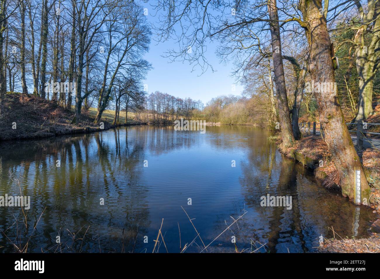 Una scena di una piscina in campagna senza persone. Il cielo è blu e leggermente increspato sull'acqua Foto Stock