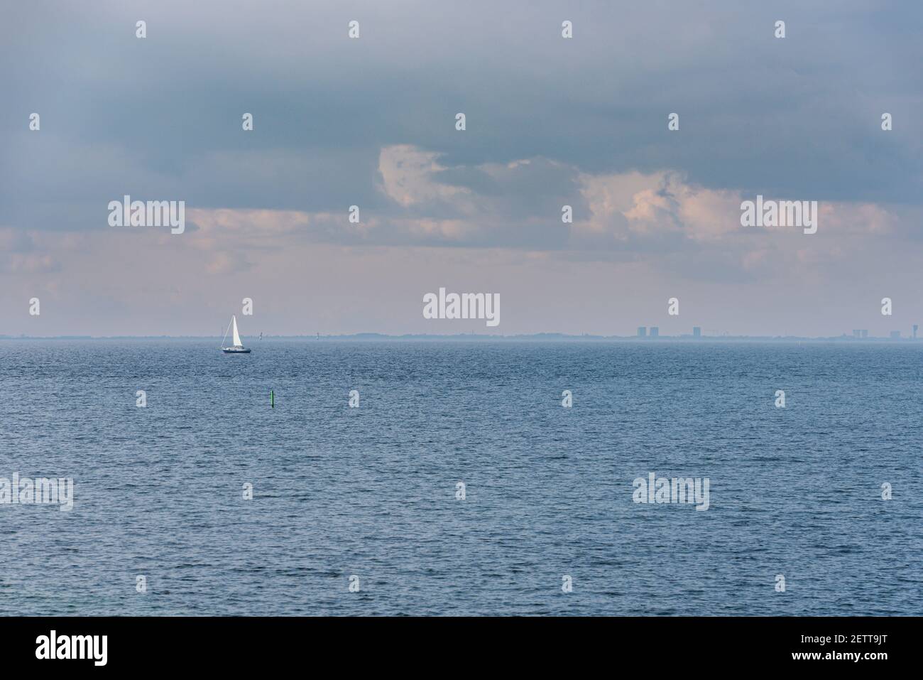 La barca a vela Lone in mare in acque calme (Strait di Oresund) su un cielo nuvoloso suggerisce relax. La barca a vela nell'oceano trasmette tranquillità e serenità Foto Stock