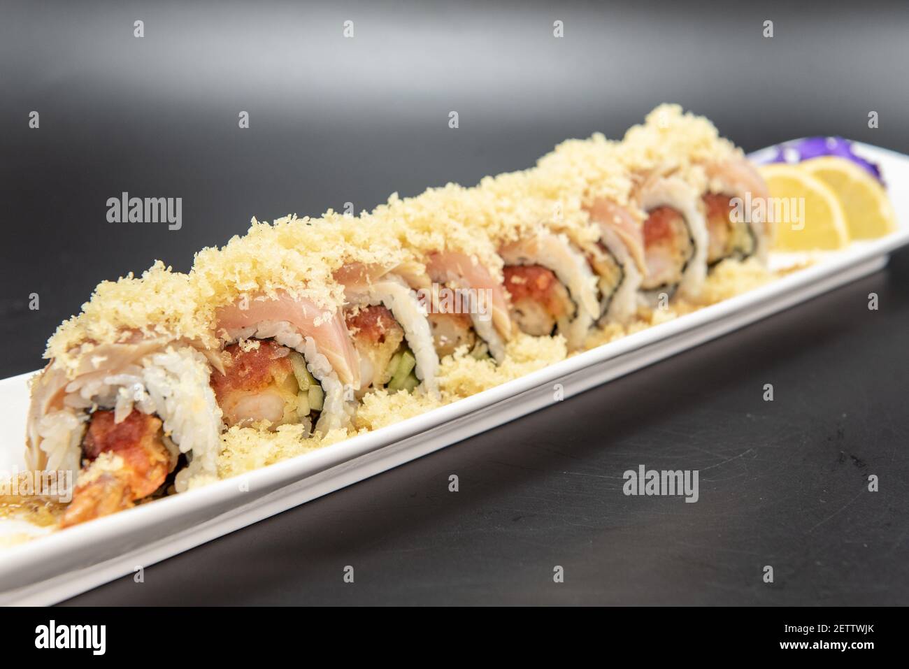 Sushi al tartufo di albaco condito con tempura croccante con bella presentazione su piatto guarnito con agrumi e un fiore. Foto Stock
