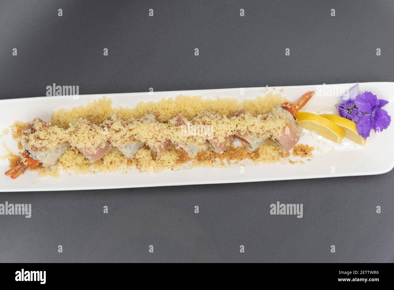 Vista dall'alto del sushi al tartufo di albacore sormontato con tempura croccante con bella presentazione su piatto guarnito con agrumi e un fiore. Foto Stock