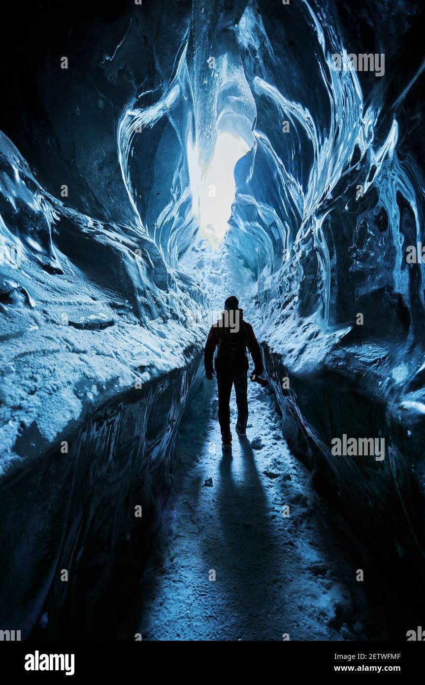 Silhouette dell'uomo che esplora una fantastica grotta glaciale di ghiaccio Le montagne in Kazakistan Foto Stock