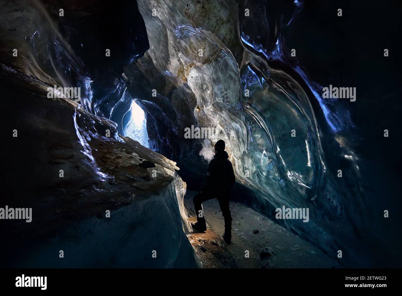 Silhouette dell'uomo che esplora una fantastica grotta glaciale di ghiaccio Le montagne in Kazakistan Foto Stock