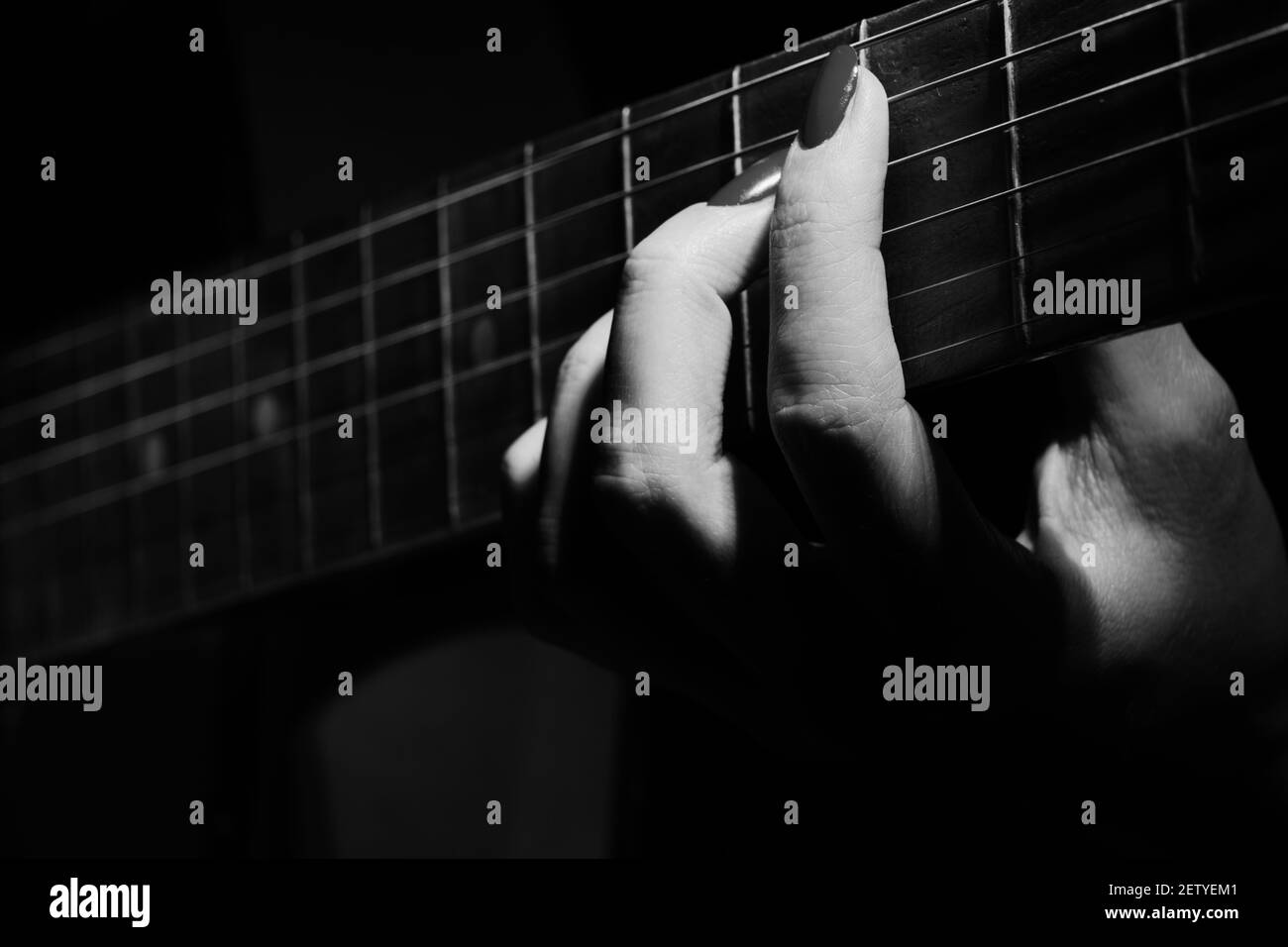 la mano femminile con corde di chitarra suona closeup monocromatico Foto Stock