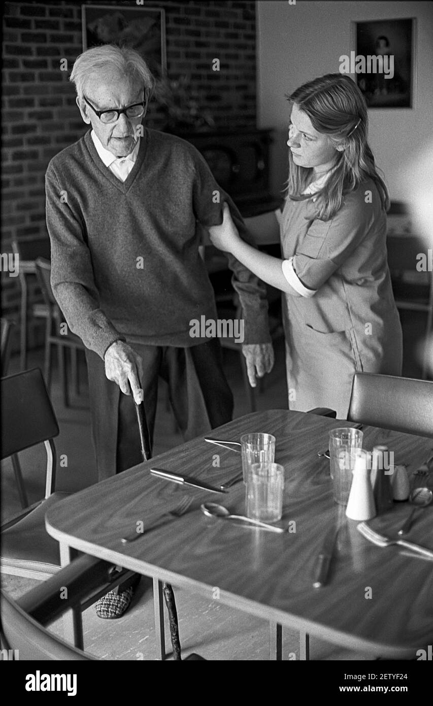 Sedici anni ragazza di scuola sul lavoro esperienza come assistente di cura in casa di cura. Aiutare l'uomo anziano a tavola. Foto Stock