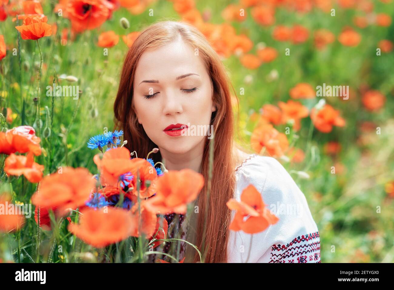 Ucraino bella Donna in ricamo tradizionale in campo papaveri ritratto esterno. Raccolta papaveri e fiore di mais in campo estivo. Pop in fiore Foto Stock