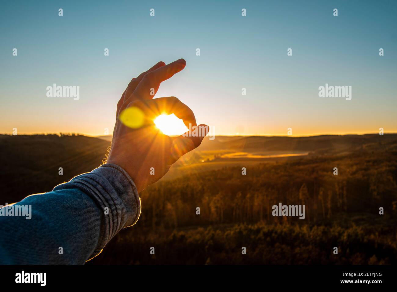 La mano maschile mostra bene al tramonto. Gesto della mano OK con il sole sullo sfondo. Foto Stock