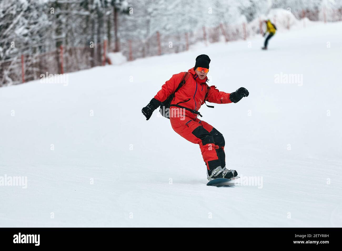 Lo snowboarder maschile in una tuta rossa corre sulla collina innevata con  concetto di snowboard, sci e snowboard Foto stock - Alamy