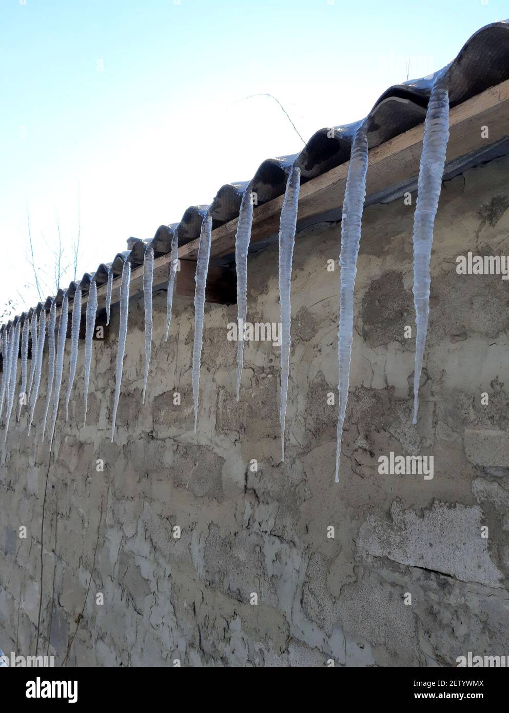 Ghiaccio in fila pendono dal tetto di una casa di mattoni. Foto Stock