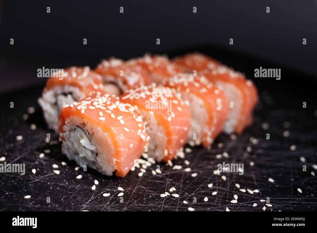 Panini di sushi di Philadelphia avvolti con salmone e formaggio di philadelphia su sfondo nero. Cibo giapponese Foto Stock