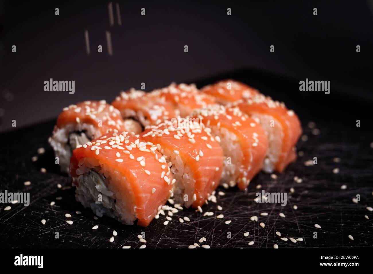 Panini di sushi di Philadelphia avvolti con salmone e formaggio di philadelphia su sfondo nero. Cibo giapponese Foto Stock