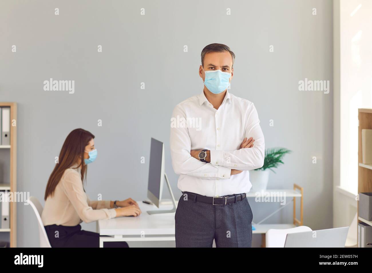 I dipendenti responsabili dell'azienda impediscono la diffusione del viso da indossare maschere al lavoro Foto Stock