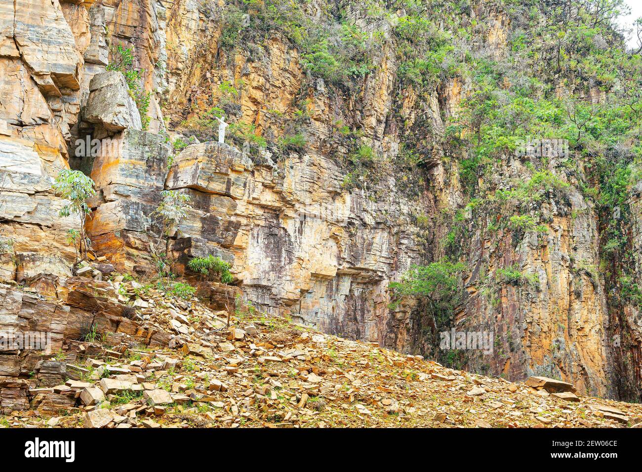 Piccola scultura bianca di Cristo a braccia aperte accanto alle pareti rocciose sedimentarie dei canyon di Furnas, a Capitólio MG Brasile. Foto Stock