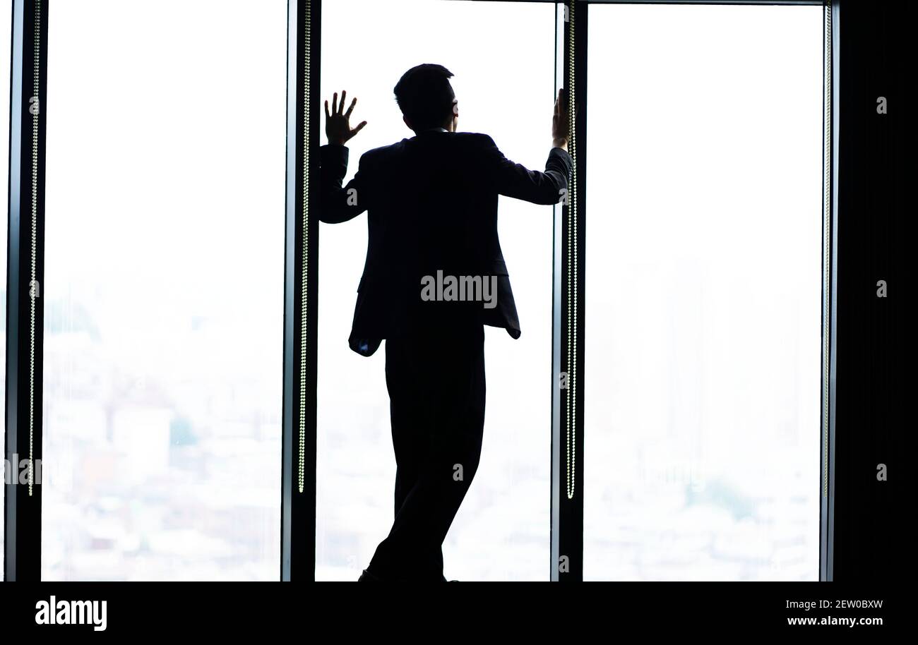 Uomo d'affari pensivo che guarda attraverso la finestra Foto Stock