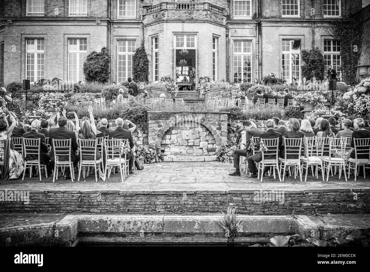 Gli ospiti seduti nei terreni di una casa padronale pronti per la sposa e lo sposo per arrivare. Foto Stock
