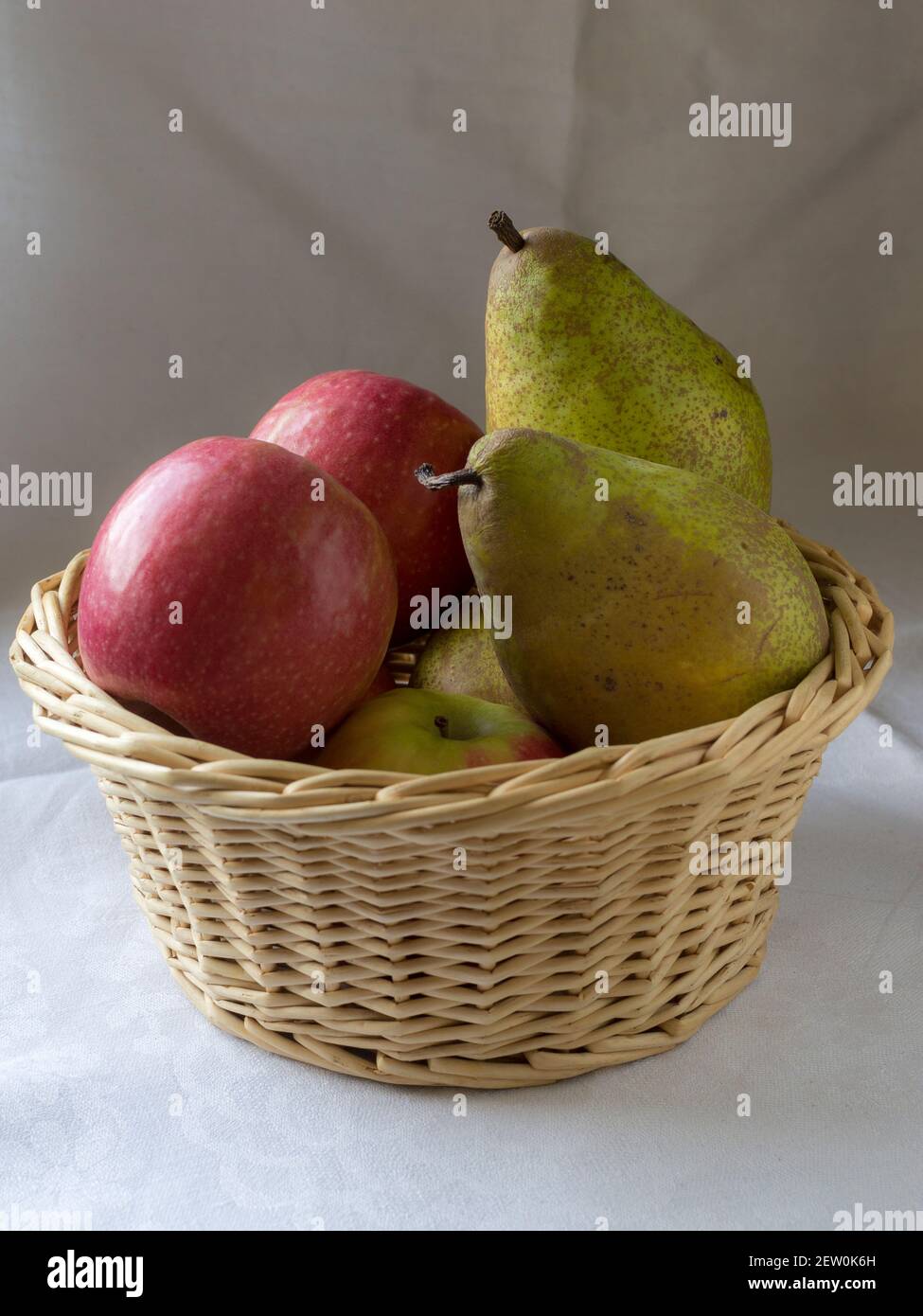 Un cesto di vimini pieno di mele e pere Foto Stock
