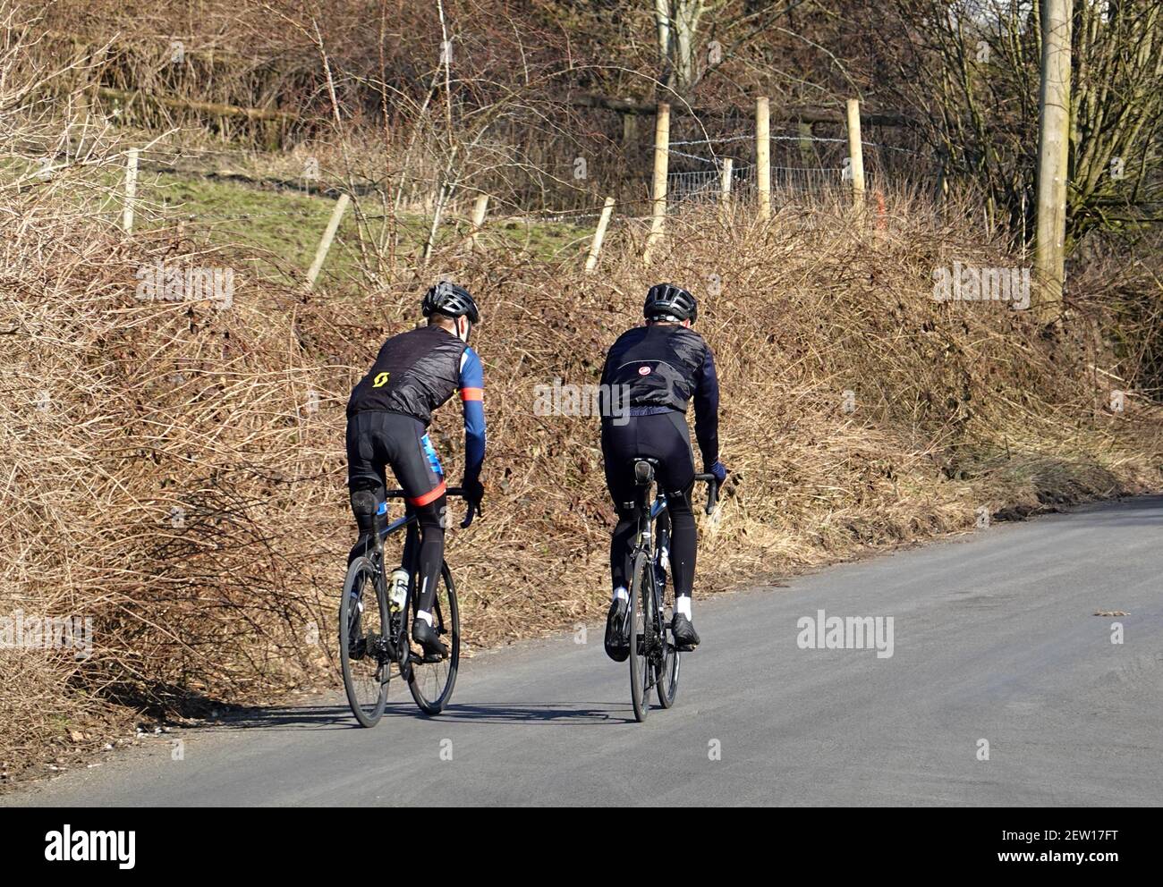 Due ciclisti che indossano abiti neri a Thornsett, Derbyshire Foto Stock